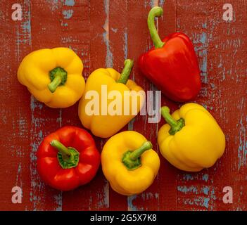 Plan view of red and yellow bell peppers on a brown and blue  wooden background. Stock Photo