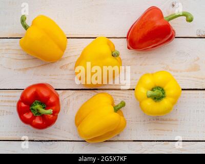Plan view of red and yellow bell peppers on a white wooden background. Stock Photo