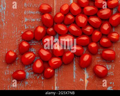 Plan view of small plum tomatoes on a brown and blue, rustic background Stock Photo