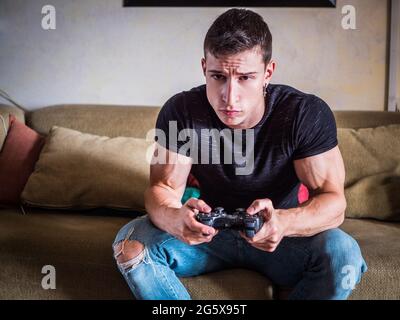 Attractive guy playing videogames with joystick in hand Stock Photo