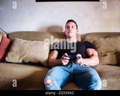 Attractive guy playing videogames with joystick in hand Stock Photo