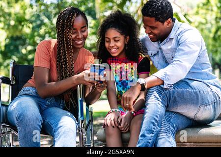 Woman in a wheelchair at the park with family. Stock Photo