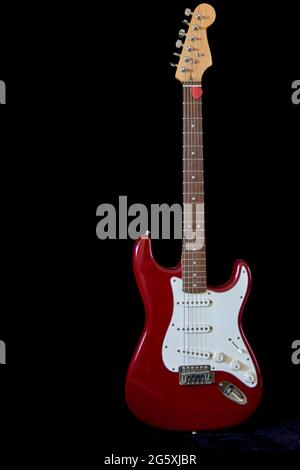 Electric guitar isolated with red plectrum on black background. vertical and copy space Stock Photo