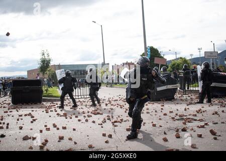 Bogota, Colombia. 29th June, 2021. A Colombia's riot police officer (ESMAD) throws rocks and debree back to demonstrators as people of Fontanar - Suba in Bogota, Colombia protested and clashed against Colombia's riot police (Escuadron Movil Antidisturbios ESMAD) against the visit of Colombia's president Ivan Duque Marquez to a park were Bogota's metro system will be built, amidst two months of anti-government protests against president Ivan Duque Marquez, inequalities and police unrest during the protests, on June 29, 2021. Credit: Long Visual Press/Alamy Live News Stock Photo