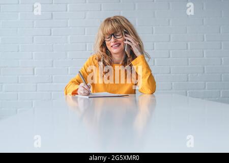 business woman talking on the phone taking notes Stock Photo