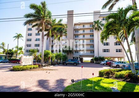 Fort Myers Beach, USA - April 29, 2018: Florida gulf coast with hotel condominium apartment building waterfront architecture and palm trees on sunny d Stock Photo