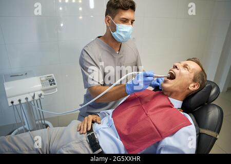 Male dentist doing treatment for man in chair Stock Photo