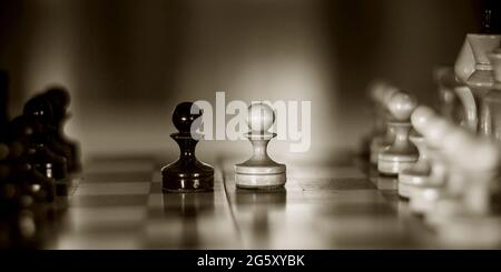 Two pieces on the chessboard are pawns: black and white. Wooden chess pieces on the chessboard. Intellectual game -chess. Chess pieces on the Board. A Stock Photo