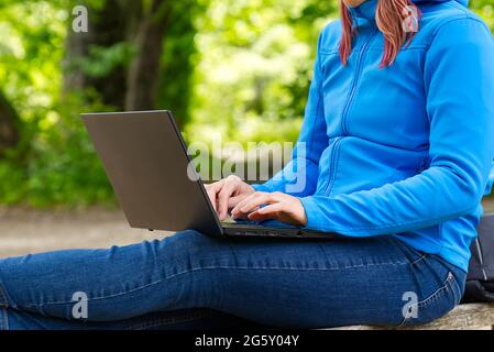 Young woman, female freelancer working with laptop with Beautiful view of forest and lake. Stock Photo