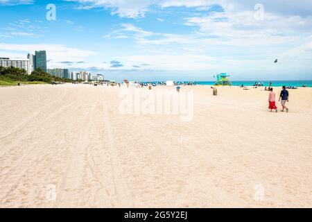 Miami Beach, USA - January 17, 2021: South Beach. Florida with people walking on beach and apartment condo hotel buildings and sand Stock Photo
