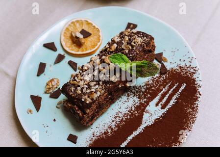 Sweet breakfast with chocolate honey biscuit cake with sour and butter cream and walnuts, a slice of dried orange and decorated with mint leaf and coc Stock Photo