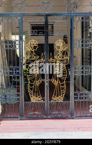 door panel on gates of entrance with gold cut out shape of classical Indian goddess carrying lit candle, Puducherry (Pondicherry), Tamil Nadu, India Stock Photo