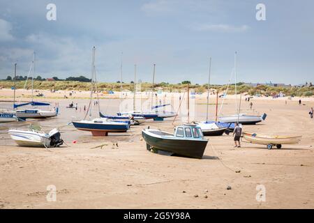 Boats on the beach at low tide, Beadnell Bay, Northumberland, UK Stock Photo
