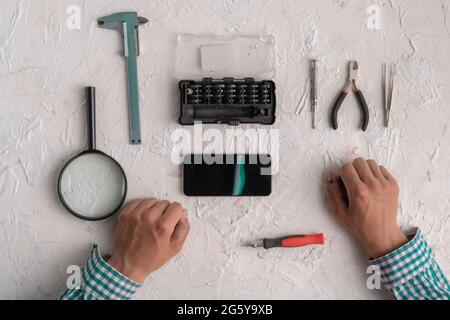 master with tools repair the broken smartphone in the workshop Stock Photo