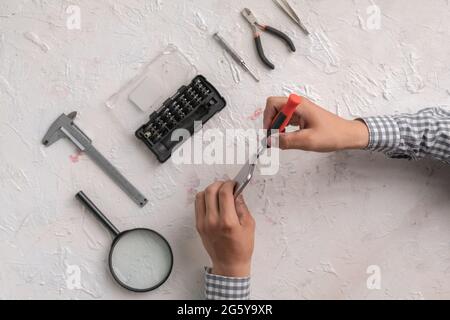 master with tools repair the broken smartphone in the workshop Stock Photo
