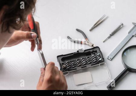 master with tools repair the broken smartphone in the workshop Stock Photo