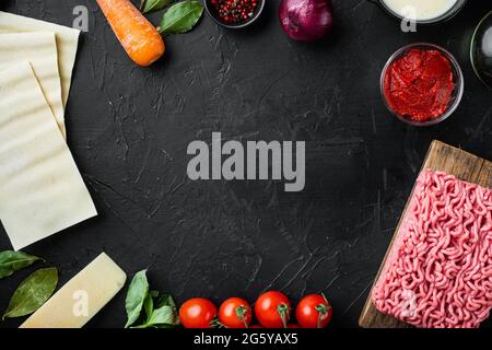 Empty space clean Frame set The concept of cooking lasagna. Italian Ingredients, lasagna sheets meat herbs tomatoes, bechamel sauce, on black stone ba Stock Photo