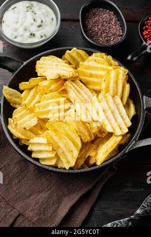 Delicious crispy potato chips, with sour cream, on old dark wooden table Stock Photo
