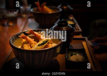 A bowl of tempura seafood with green peppers sitting on a table in Roppongi, a suburb of Tokyo, Japan.