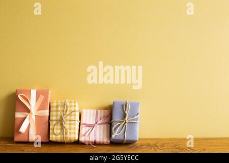Colorful gift boxes on wooden table. yellow wall background Stock Photo