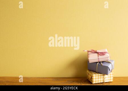 Colorful gift boxes on wooden table. yellow wall background Stock Photo