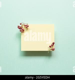 Yellow memo pad with red fruits on blue background. top view, copy space Stock Photo
