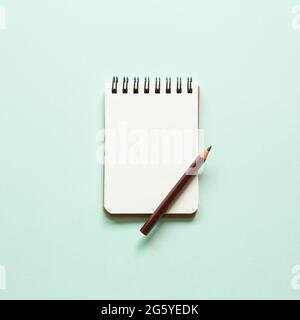 Blank notebook and colored pencil on blue background. top view, copy space Stock Photo