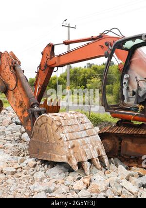 orange, rusty, worn out bulldozer excavators on site doing construction works during the afternoon in a barren land Stock Photo