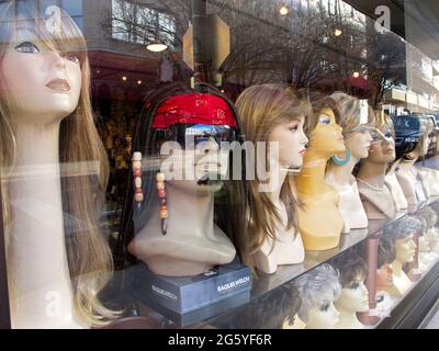 Wigs are displayed in a storefront window. Stock Photo