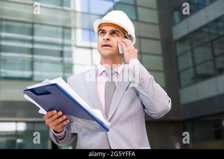 Businessman with papers talking on phone Stock Photo