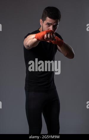 Young boxer performing right jab with hand wrapped in red tape Stock Photo