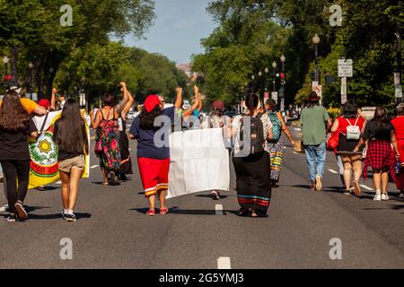Washington, DC, USA. 30th June, 2021. Pictured: Demonstrators march with raised fists on Constitution Avenue in downtown Washington during the morning rush hour. They are calling on the Biden Administration and Congress to prioritize climate justice and indigenous rights and stop further development of fossil fuel extraction. Credit: Allison Bailey/Alamy Live News Stock Photo