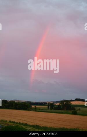 rainbow in red dusk clouds Stock Photo