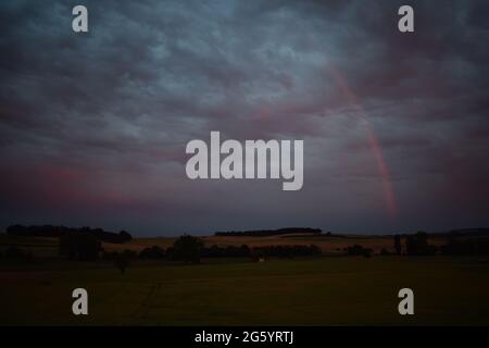 rainbow in red dusk clouds Stock Photo