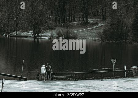 Young couple near lake at late fall rear view. Black and white photo Stock Photo