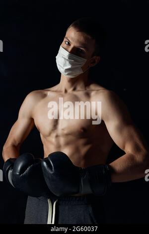 portrait of sportsman wearing boxing gloves and medical mask close-up cropped view  Stock Photo