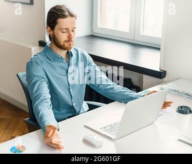 Calm male office worker meditating with closed eyes at work Stock Photo