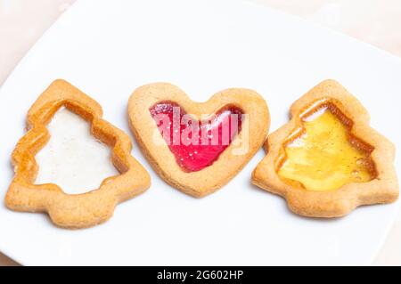 Shapes of gingerbread with colored isomalt, on a white plate. Noel gingerbread cookies. Stock Photo