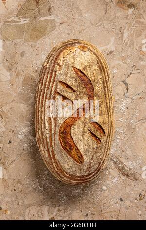 Flat plan view of handmade artisanal sourdough bread on a light brown marble work surface. Freshly baked. Stock Photo