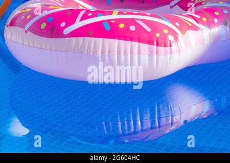 A colourful inflatable plastic ring floating in an outdoor pool. Stock Photo