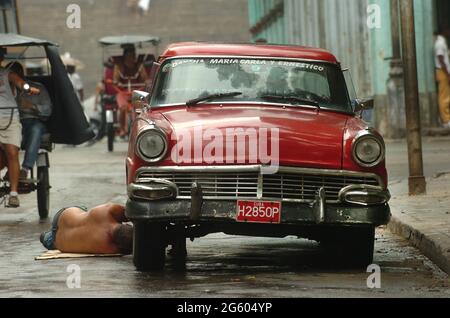 Man repairing his old car in the streets of Havana, Cuba May 2006. cars repairs repair maintenance  Cuban men classic vintage car breakdown repair Stock Photo