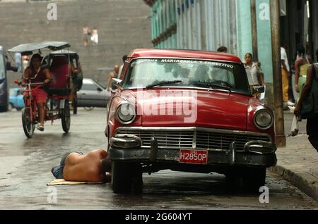 Man repairing his old car in the streets of Havana, Cuba May 2006. cars repairs repair maintenance  Cuban men classic vintage car breakdown repair Stock Photo