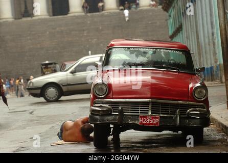 Man repairing his old car in the streets of Havana, Cuba May 2006. cars repairs repair maintenance  Cuban men classic vintage car breakdown repair Stock Photo