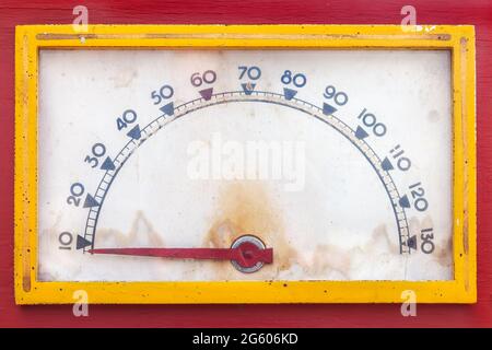 Vintage weathered meter with red needle in a red casing with yellow frame Stock Photo