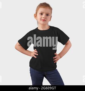 Template of branded children’s clothing on a cute baby in blue jeans, posing, front view, empty kidswear on a background in the studio. Mockup Black J Stock Photo