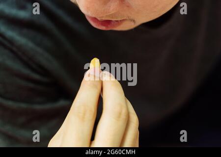 Young Asian man feeling sick and taking pills while sitting on the bed at home with medicines tablets and drinking water on table. Healthcare and Medicine concept Stock Photo