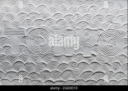 Japanese Zen garden raked with the word TOKYO in capital letters in textured white sand with wave pattern Stock Photo