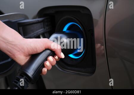 Woman charging car using electric plug closeup Stock Photo