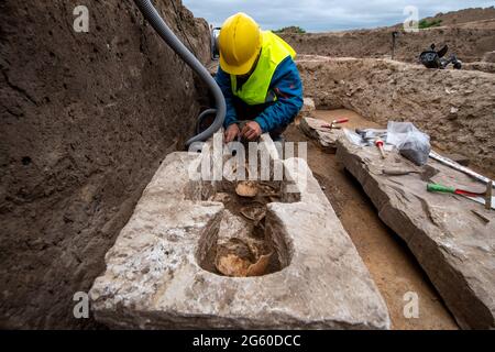 Eisleben, Germany. 1st July 2021. An archaeologist examines a sarcophagus on the site of the former royal palace of Helfta. Archaeologists from the Saxony-Anhalt State Office for the Preservation of Monuments and Archaeology had already begun weeks ago to uncover the foundation walls of the church of Emperor Otto the Great (912-973). In the process, the archaeologists came across a large number of burials, including several stone crypts from the 10th to 15th centuries. Credit: dpa picture alliance/Alamy Live News Stock Photo