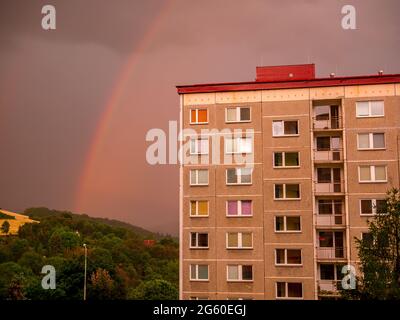 Rainbow over the house with dense rain clouds in the background Stock Photo